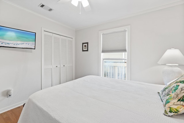 bedroom with ornamental molding, a closet, wood finished floors, and visible vents