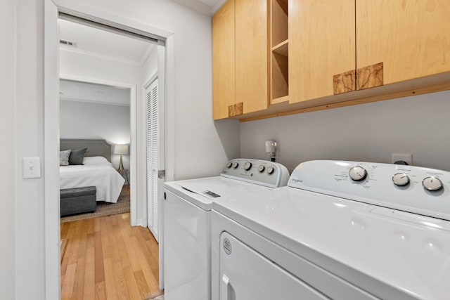 washroom featuring cabinet space, light wood finished floors, visible vents, crown molding, and separate washer and dryer