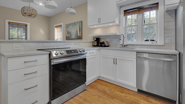 kitchen with a peninsula, plenty of natural light, appliances with stainless steel finishes, and a sink