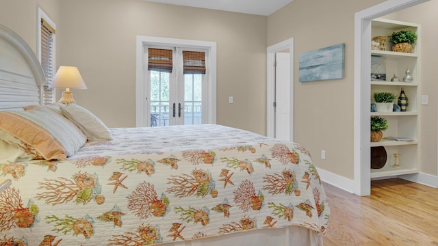 bedroom featuring access to outside, baseboards, wood finished floors, and french doors