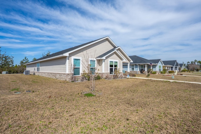 view of front of home with cooling unit, brick siding, and a front lawn