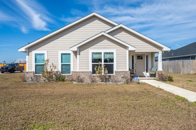 view of front facade featuring fence, a front lawn, and brick siding