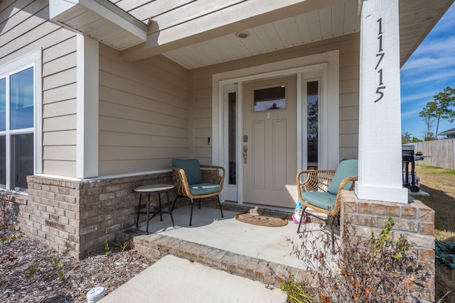 property entrance with a porch and brick siding