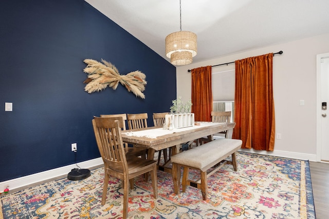 dining area with lofted ceiling, an inviting chandelier, baseboards, and wood finished floors