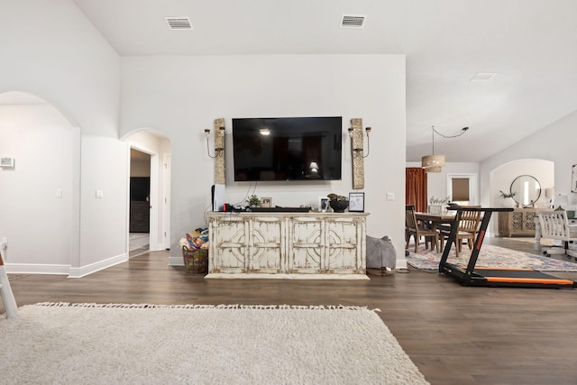 living room with arched walkways, visible vents, baseboards, and wood finished floors