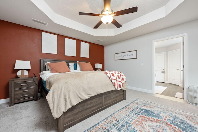 bedroom with a raised ceiling, visible vents, light carpet, and baseboards