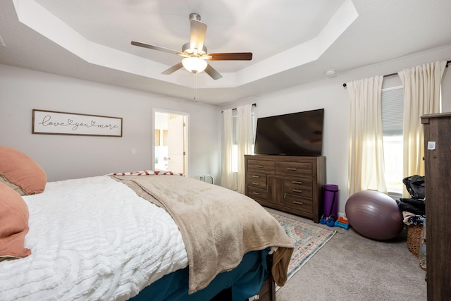 carpeted bedroom with a ceiling fan and a raised ceiling