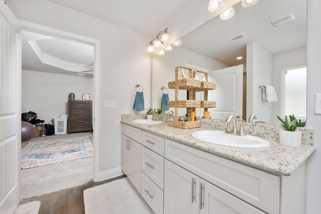 bathroom with double vanity, visible vents, a sink, and wood finished floors