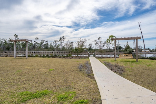 view of property's community with a yard, fence, and a pergola