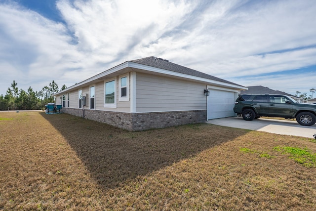 view of home's exterior with a garage, concrete driveway, brick siding, and a yard