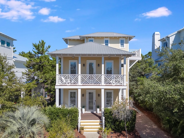 view of front of property featuring a porch, a standing seam roof, metal roof, and a balcony