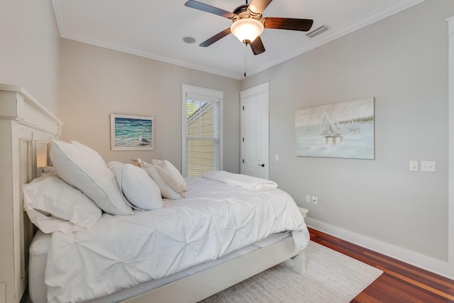 bedroom with visible vents, crown molding, baseboards, and wood finished floors