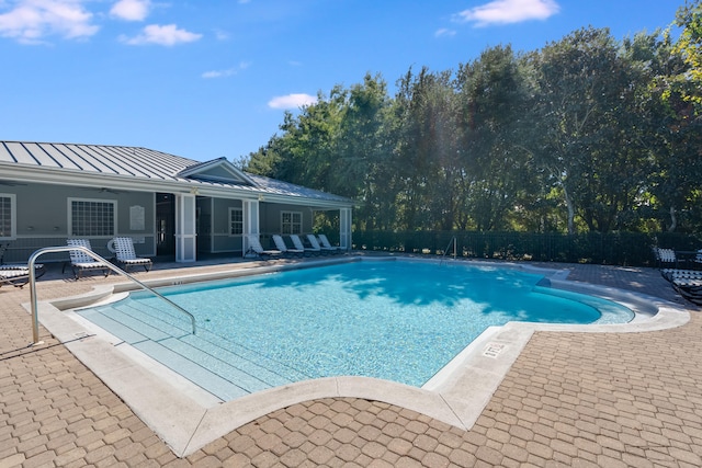 pool with a patio area, fence, and ceiling fan