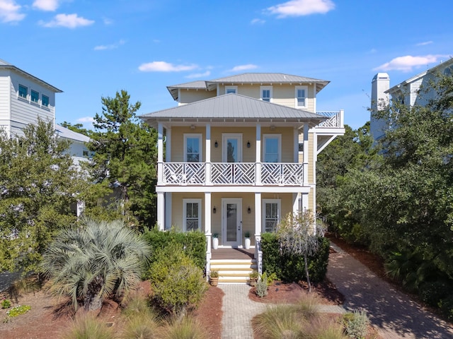 view of front facade featuring a balcony, metal roof, a porch, and a standing seam roof