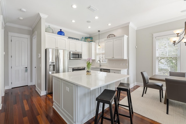 kitchen featuring hanging light fixtures, appliances with stainless steel finishes, light countertops, and white cabinets