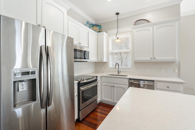 kitchen with decorative light fixtures, stainless steel appliances, light countertops, white cabinets, and a sink