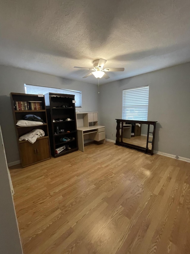 interior space featuring light wood-style floors, plenty of natural light, a textured ceiling, and a ceiling fan