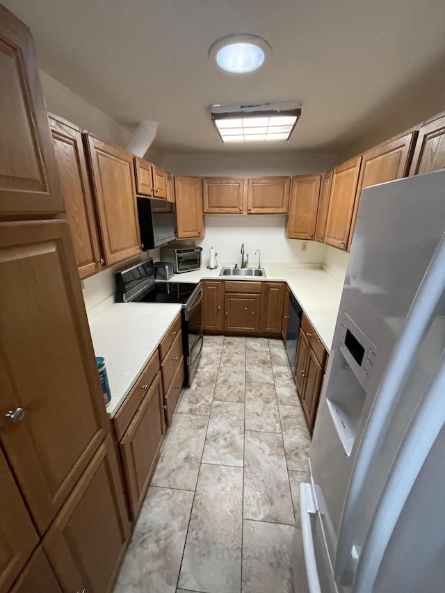 kitchen featuring black appliances, light countertops, and a sink