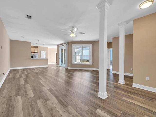 unfurnished living room with hardwood / wood-style flooring, ornate columns, and ceiling fan