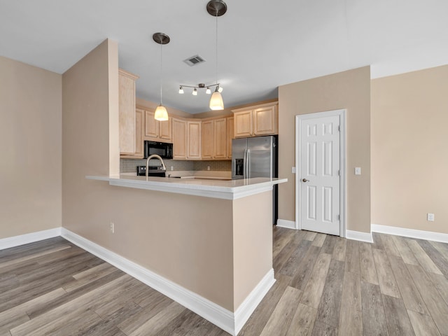 kitchen with light hardwood / wood-style flooring, stainless steel appliances, light brown cabinetry, and kitchen peninsula