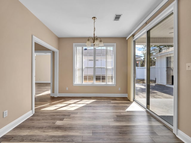 unfurnished dining area featuring hardwood / wood-style flooring and a chandelier