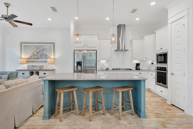 kitchen featuring stainless steel appliances, visible vents, open floor plan, a kitchen island with sink, and wall chimney exhaust hood