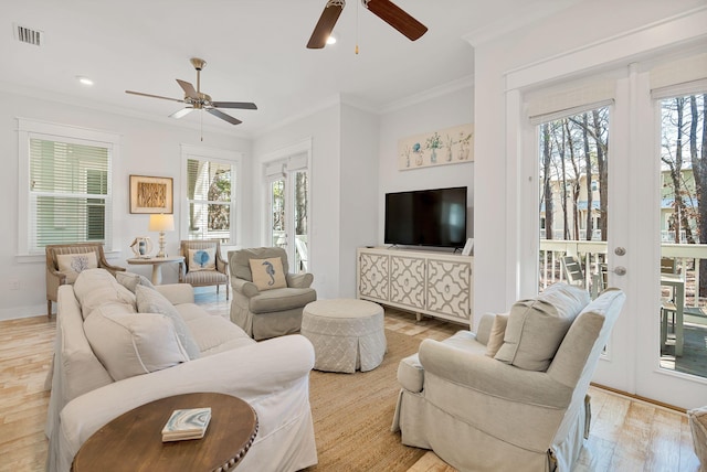 living room featuring baseboards, visible vents, a ceiling fan, crown molding, and light wood-style floors