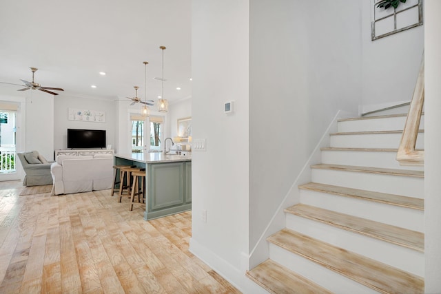 staircase with baseboards, a ceiling fan, wood-type flooring, crown molding, and recessed lighting