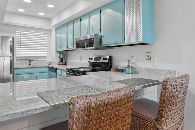 kitchen featuring blue cabinetry, stainless steel appliances, recessed lighting, light countertops, and a sink