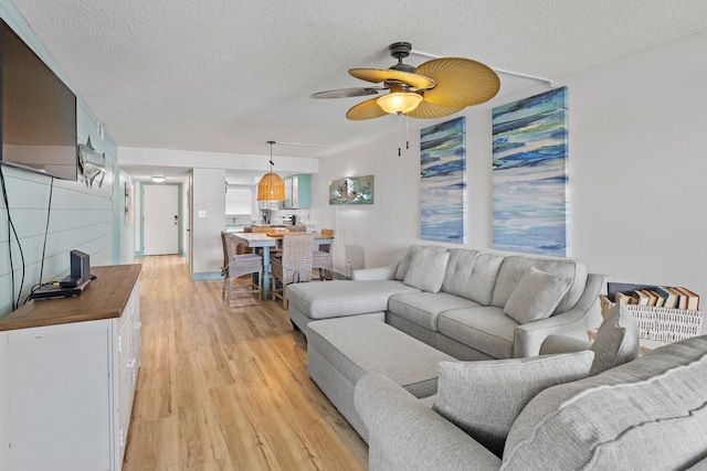 living area featuring a textured ceiling, ceiling fan, and light wood-type flooring