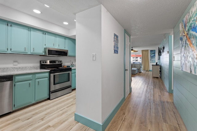 kitchen featuring baseboards, appliances with stainless steel finishes, light countertops, a textured ceiling, and light wood-style floors