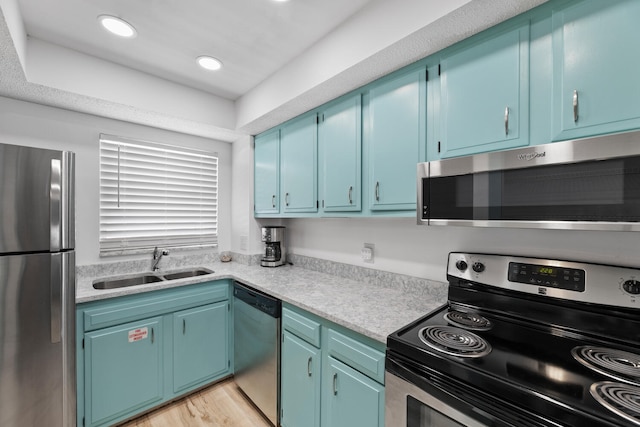 kitchen featuring light countertops, appliances with stainless steel finishes, a sink, and light wood-style flooring