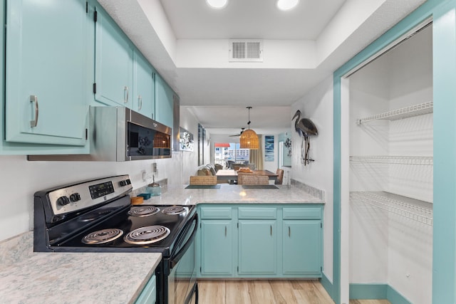 kitchen featuring visible vents, appliances with stainless steel finishes, decorative light fixtures, light countertops, and light wood-type flooring