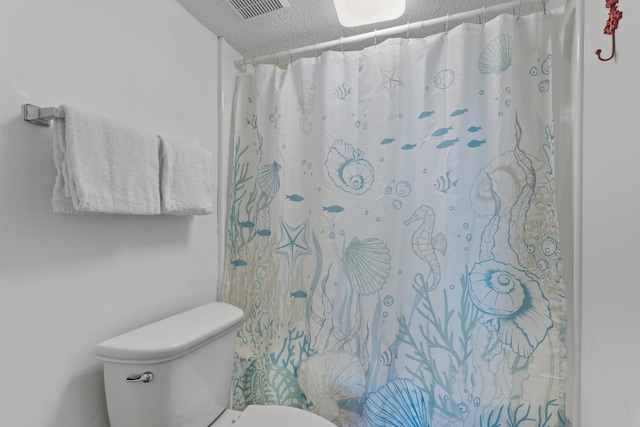 full bathroom featuring toilet, a shower with curtain, visible vents, and a textured ceiling