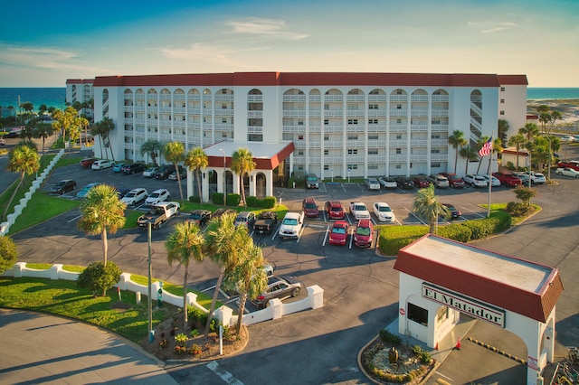 property at dusk with uncovered parking and a water view