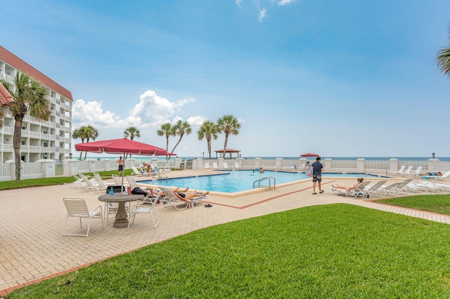 community pool featuring a lawn, fence, and a patio