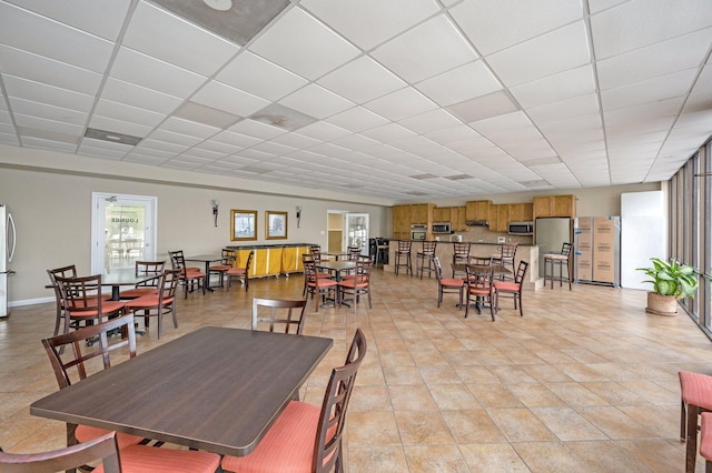 dining space with a drop ceiling and baseboards