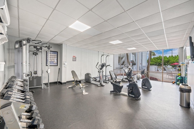 workout area with a paneled ceiling and a wall of windows