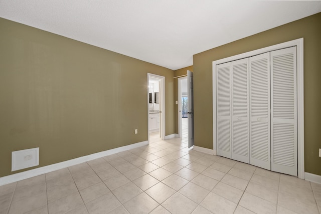 unfurnished bedroom featuring light tile patterned floors, a closet, and baseboards