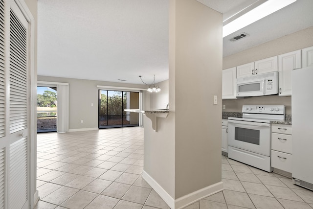 kitchen with a chandelier, light tile patterned flooring, white appliances, visible vents, and white cabinets