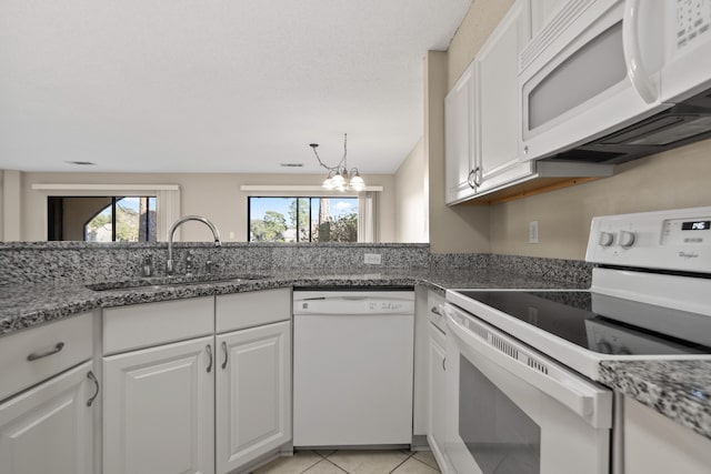 kitchen with light tile patterned floors, white appliances, a sink, and white cabinets