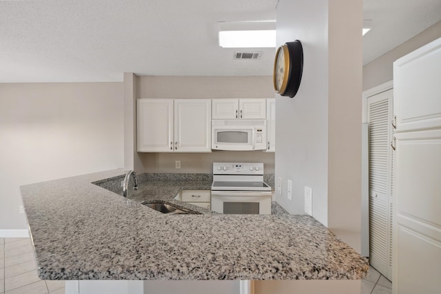 kitchen with visible vents, white cabinetry, a sink, white appliances, and a peninsula