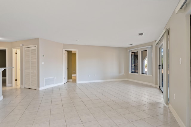 spare room with light tile patterned flooring, visible vents, and baseboards