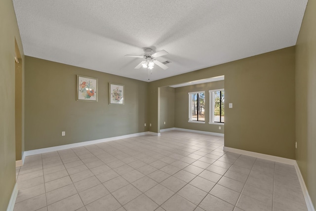 spare room with ceiling fan, baseboards, a textured ceiling, and light tile patterned flooring