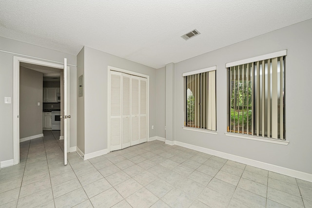 303 Southlake Ct Unit 303, Niceville, FL 32578 - unfurnished bedroom with light tile patterned floors, a closet, a textured ceiling, baseboards, and electric panel