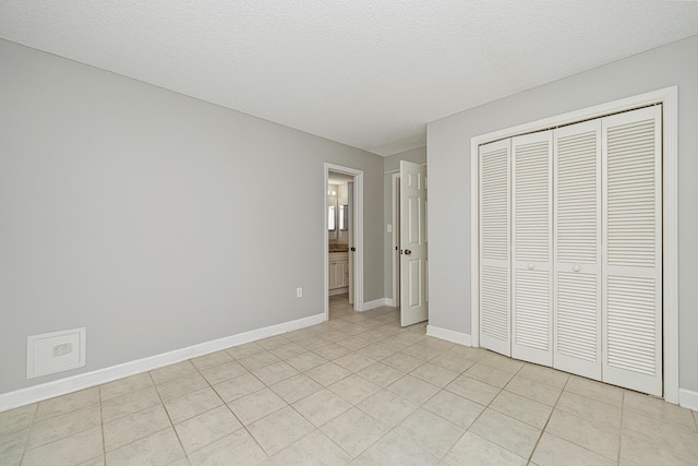 303 Southlake Ct Unit 303, Niceville, FL 32578 - unfurnished bedroom featuring baseboards, light tile patterned floors, a closet, and ensuite bathroom