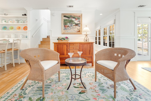 sitting room with visible vents, ornamental molding, and light wood finished floors