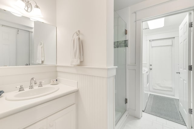 full bath with vanity, a shower stall, and a wainscoted wall