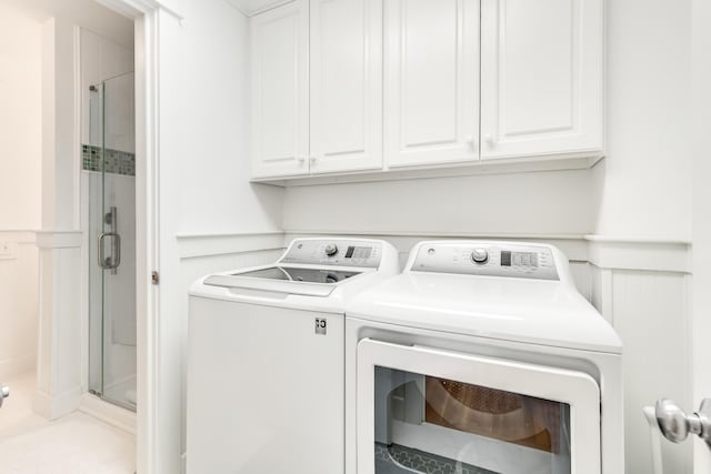 laundry area featuring washing machine and clothes dryer, a wainscoted wall, and a decorative wall