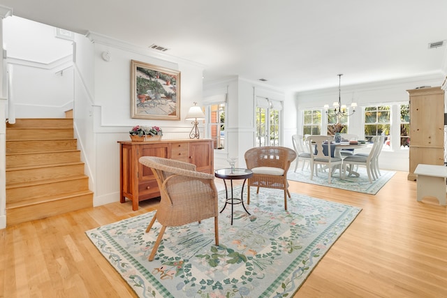 sitting room with stairway, visible vents, ornamental molding, and light wood finished floors